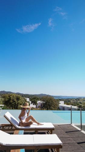 a woman sitting on a lounge chair next to a pool at Montimerso Skyscape Countryhouse in Monsaraz
