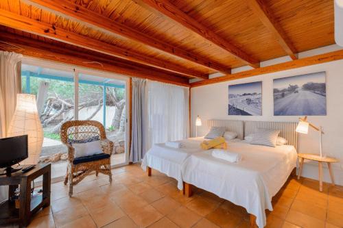 a bedroom with a bed and a chair and a television at Ponent in Es Caló