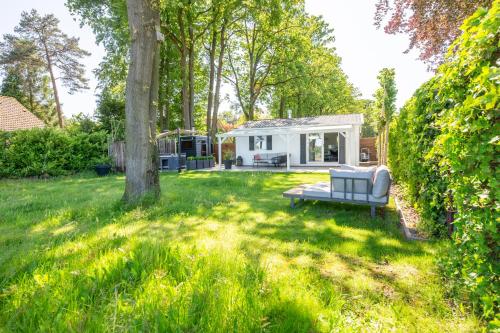 einen Hinterhof mit einer Couch im Gras in der Unterkunft 86, Bed & Outdoor Wellness - Sauna, Hottub, Icebath & Outdoor Shower included! in Oisterwijk