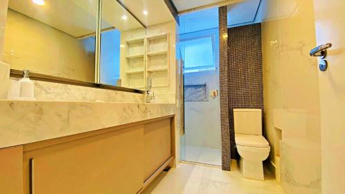 a bathroom with a toilet and a glass shower at Apto cinematográfico vista mar in Guarujá