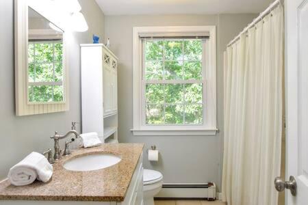 een badkamer met een wastafel, een toilet en een raam bij Quiet Location Near Oceanside Beaches in Eastham