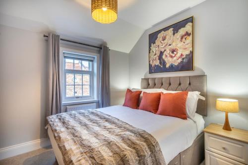 een slaapkamer met een bed met oranje kussens en een raam bij Middlethorpe Manor - No 3 in York