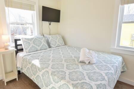a bedroom with a bed with a blue comforter and two windows at 4 Min Drive to Bayside Beaches in Eastham