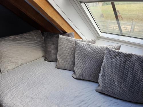 a bed with four pillows sitting next to a window at Alpaca House - Sleeps 17 - DIY Hot Tub in Gravesend