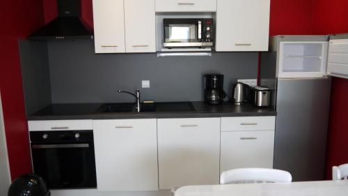une cuisine avec des armoires blanches et un micro-ondes dans l'établissement Appart 4/6 pers proche centre et acces direct plage : Ouessant, à La Bernerie-en-Retz