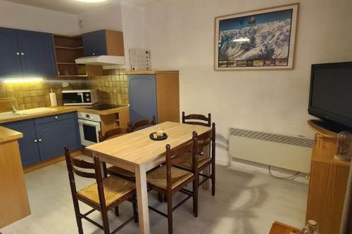cocina con mesa y sillas y TV en Appartement 4/6 places pied des pistes, en Saint-Lary-Soulan