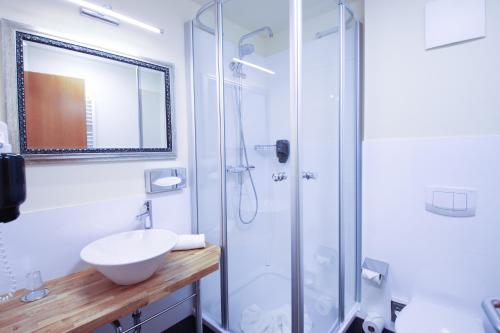 a white bathroom with a sink and a shower at Boutique Hotel Schwarzer Baer in Lutherstadt Wittenberg