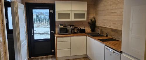 a kitchen with white cabinets and a microwave on a counter at San Escobar Dziwnówek in Dziwnówek