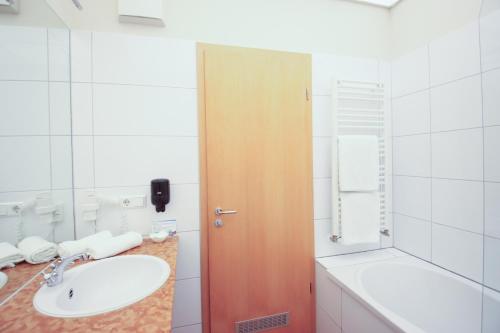 a bathroom with a sink and a wooden door at Boutique Hotel Schwarzer Baer in Lutherstadt Wittenberg