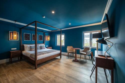 - une chambre avec des murs bleus, un lit et un bureau dans l'établissement Açores Autêntico Boutique Hotel, à Angra do Heroísmo