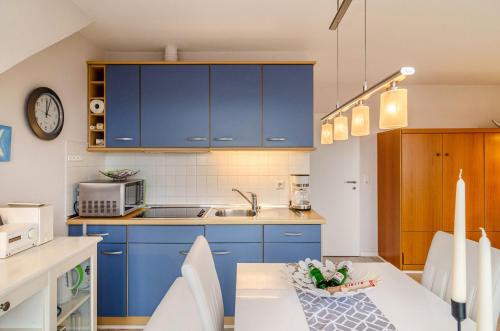 a kitchen with blue cabinets and a table with chairs at Ferienhaus Raschke in Norderney