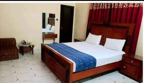 a bedroom with a large bed and a red curtain at Best Couple Coprtive Guest House in Karachi