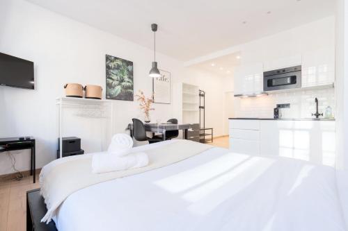 - une chambre blanche avec un grand lit et une cuisine dans l'établissement Superbe appartement sur la Grand Place, avec vue !, à Lille
