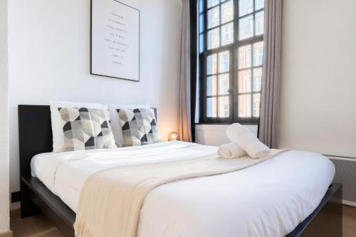 une chambre avec un lit avec des draps blancs et une fenêtre dans l'établissement Superbe appartement sur la Grand Place, avec vue !, à Lille
