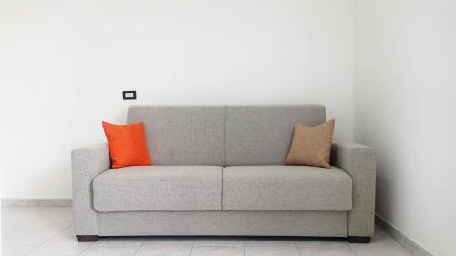 a gray couch with two orange pillows on it at Terrazza Bianca in Vittoria