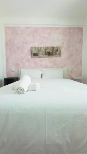 a bedroom with a white bed with a pink wall at Terrazza Bianca in Vittoria
