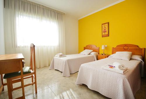 a room with two beds and a desk and a window at Apartamentos en Playa de Montalvo in Sanxenxo