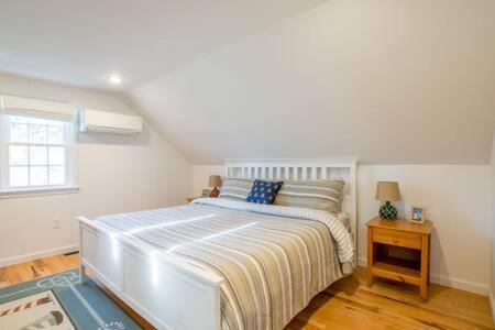 a white bedroom with a bed and a window at Central AC Close to Beach Dog Friendly! in Chatham