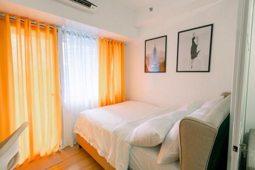 a bedroom with orange curtains and a white bed at Frost at Air Residences Makati in Manila