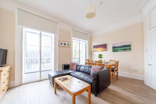 uma sala de estar com um sofá de couro preto e uma mesa em Spacious & Central 3-bed flat by popular Waterloo! em Londres