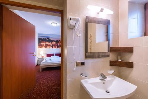 a bathroom with a sink and a mirror and a bed at Hotel Karolek in Zawoja