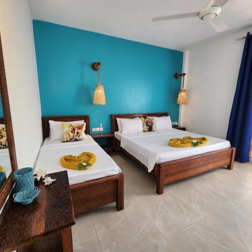 - une chambre avec 2 lits et un mur bleu dans l'établissement Olzadia Boutique Hotel, à Michamvi