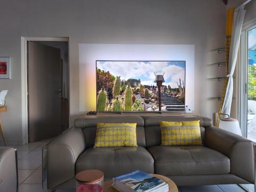 una sala de estar con un sofá con una foto en la pared en Villa Nadia - Prestige et Confort Absolu avec Vue Imprenable sur la Mer, en Le Diamant