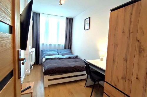 a small bedroom with a bed and a desk at Apartament Górski Widok in Duszniki Zdrój