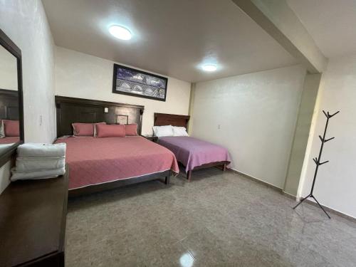 - une chambre avec 2 lits avec des draps roses dans l'établissement HOTEL OTOMI, à Otumba de Gómez Farías