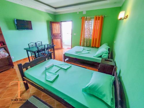 2 Betten in einem Zimmer mit grünen Wänden in der Unterkunft TOKY Hôtel in Antsirabe