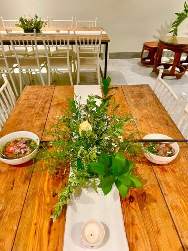 a wooden table with two bowls and flowers on it at Hoàng Khang Hotel- Khách Sạn Buôn Ma Thuột in Buôn Kô Sir