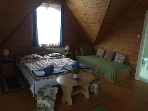 ein Schlafzimmer mit einem Bett, einem Sofa und einem Tisch in der Unterkunft Hubertus Vendégház in Parád