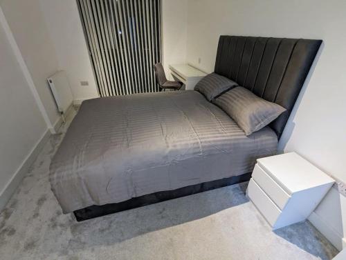 ein Schlafzimmer mit einem großen Bett und einem weißen Tisch in der Unterkunft NEW Lux 1 or 2 Bed Flats + Car Park + 5min Tube + Fast WiFi in London