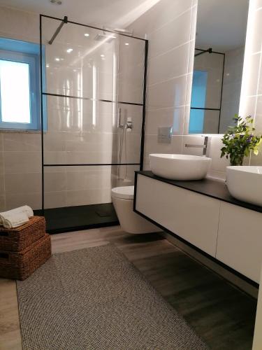 a bathroom with two sinks and a glass shower at Casa de Férias do Parque da Peneda 2 in Vila Verde