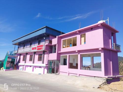 un bâtiment rose sur le côté d'une route dans l'établissement Hotel heavenly heights, à Dhanaulti