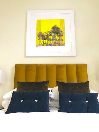 a bed with blue pillows and a picture above it at Cloud Nine Luxe Apartment in London