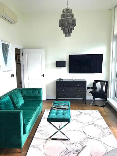 a living room with a green couch and a tv at Cloud Nine Luxe Apartment in London