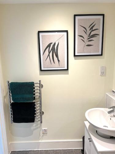 a bathroom with two pictures on the wall and a sink at Cloud Nine Luxe Apartment in London