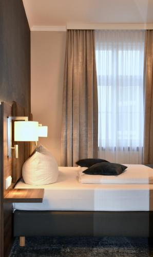 a bed with a white pillow and a window at Schwarzer Bär Jena in Jena