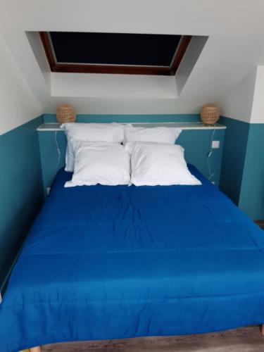 - un lit bleu avec des oreillers blancs dans l'établissement Petite maison proche plage 2/4 p, à La Bernerie-en-Retz