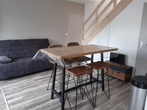 einen Tisch und Stühle im Wohnzimmer mit Sofa in der Unterkunft Petite maison proche plage 2/4 p in La Bernerie-en-Retz
