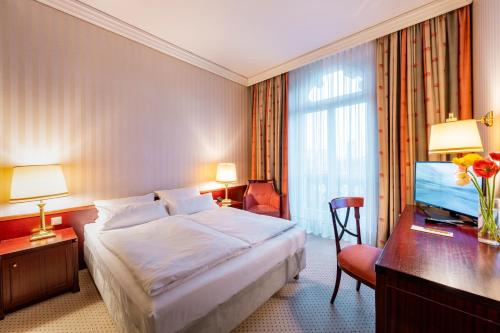 Cette chambre comprend un lit, un bureau et une télévision. dans l'établissement Parkhotel 1901 Mannheim, à Mannheim