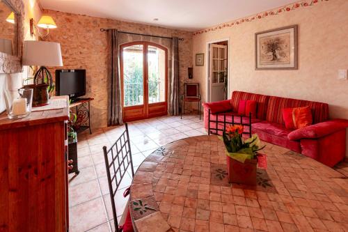 a living room with a red couch and a table at Mas du Clos de l'Escarrat in Jonquières
