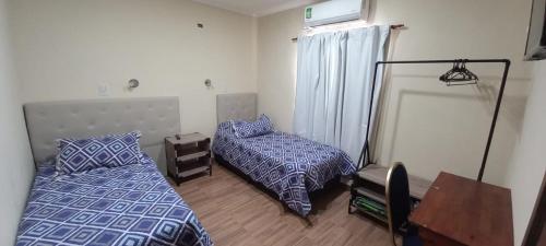 a bedroom with two beds and a table and a desk at Alemar Termas Hotel in Termas de Río Hondo