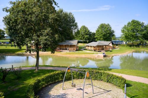 uma vista aérea de um lago com casas e um parque infantil em Glamping Betuwe em Kesteren