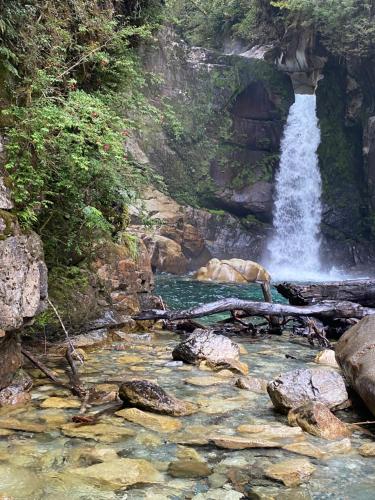 a waterfall and a pool of water with rocks at La Casona Puelo Lodge in Cochamó