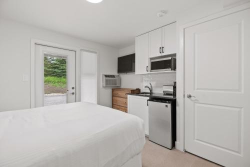 a white bedroom with a bed and a kitchen at Touchstone Resort in Bracebridge