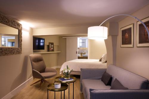 a hotel room with a bed and a couch and chairs at Vrachos Athens Suites in Athens