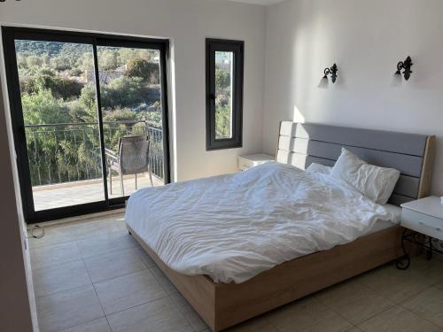 1 dormitorio con 1 cama grande y balcón en Grand süit 402, en Kalkan