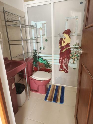 - une salle de bains avec des toilettes et une peinture d'une femme dans l'établissement Casa de 3 recamaras frente al parque, à Mérida